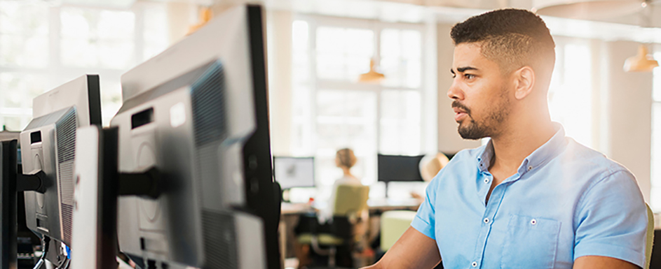 man sitting behind dual computer monitors